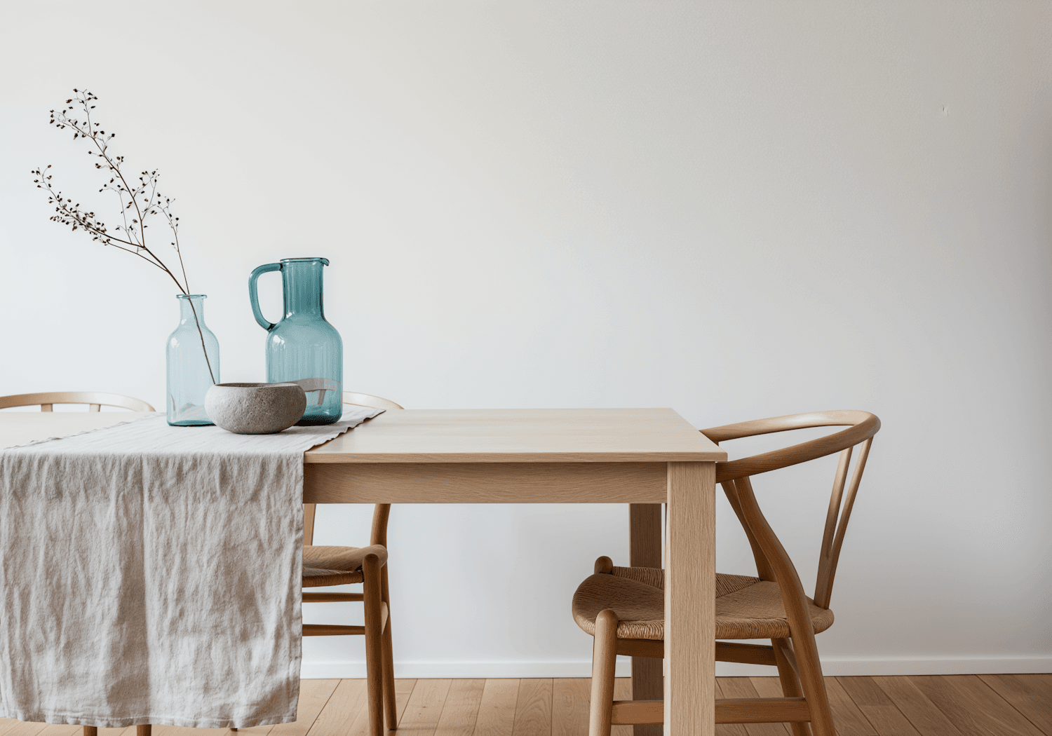 Long minimalist oak dining table set with linen runner and stone bowl